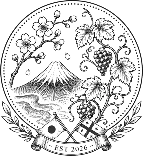 Japan Georgia Trading Corporation-ის ემბლემა: წერტილოვან წრეში მარცხნივ ალუბლის ყვავილოვანი ტოტი, ფუძის მთა და მდინარე, მარჯვნივ ვაზი; ქვემოთ იაპონიისა და საქართველოს დროშები იკვეთება ლენტზე წარწერით „EST 2026“